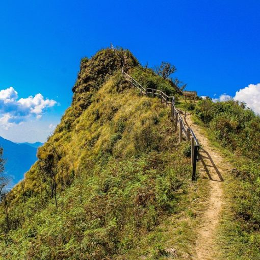 image of mountain top in thailand with blue sky and green grass and a walking path for hot yoga teacher training